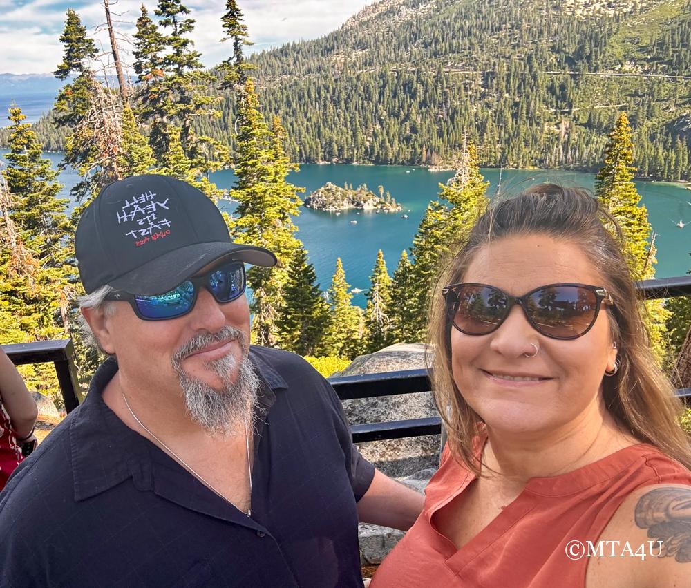 Photo of Noel and Illya from MTA4U standing together at Lake Tahoe Inspiration Point, with a panoramic view of Emerald Bay and its surrounding mountains in the background.