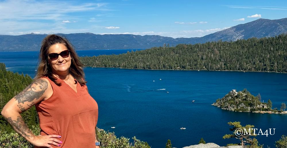 Photo of Noel from MTA4U standing at the Vikingsholm Castle parking lot overlook, with a stunning view of Emerald Bay and the surrounding forest in the background