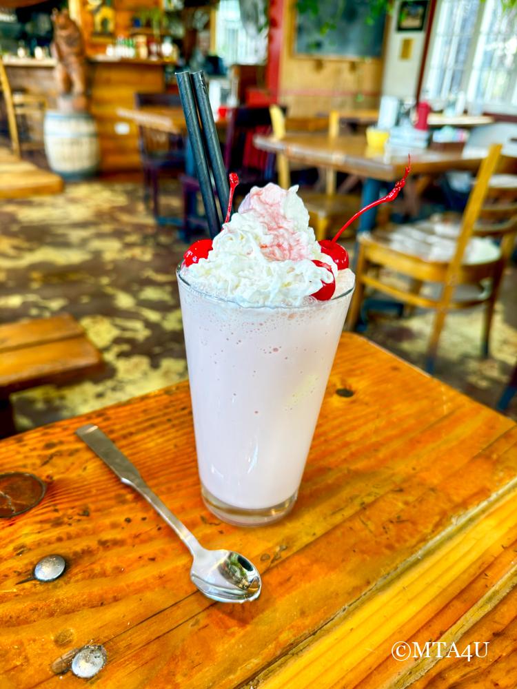 Thick strawberry milkshake with whipped cream and cherries on top.