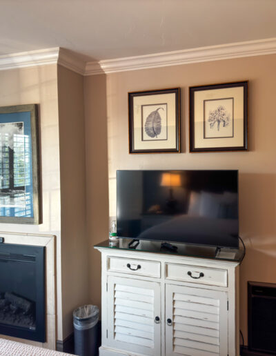 Guest room at Sand Pebbles Inn with a TV, fireplace, and coastal decor.