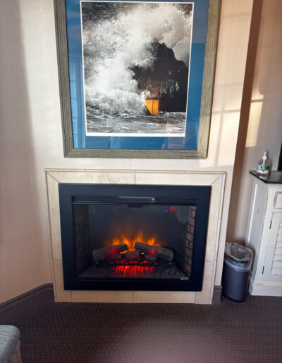 Cozy fireplace corner at Sand Pebbles Inn with coastal artwork and soft lighting.