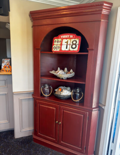 Decorative red shelf in Sand Pebbles Inn lobby with coastal decor and date display.