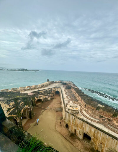 Aerial view of El Morro fortress in San Juan, Puerto Rico, showing historic architecture and the Atlantic Ocean in the background.