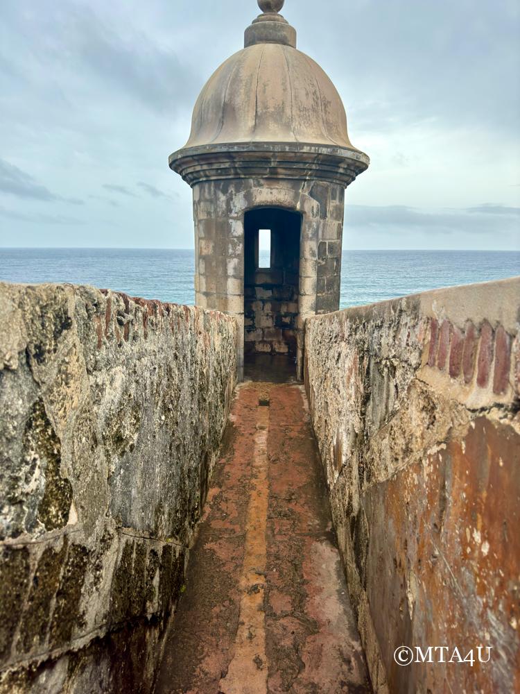 Historic watchtower at El Morro fortress in San Juan, Puerto Rico, overlooking the ocean and coastline.