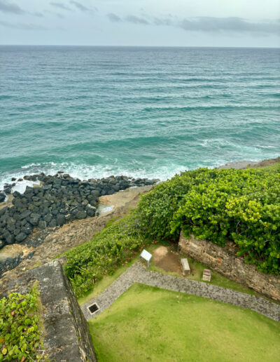 View of the Atlantic Ocean and a green courtyard within El Morro fortress in San Juan, Puerto Rico