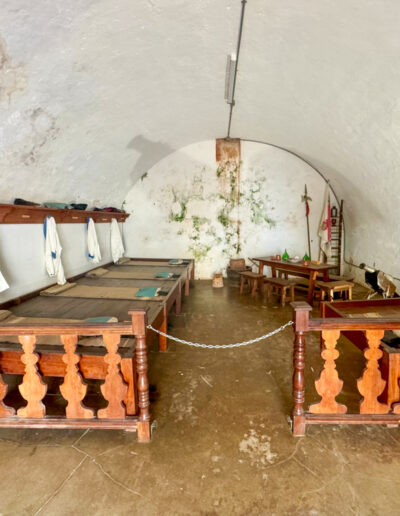 Interior view of a barracks room with wooden bunk beds and rustic decor at El; Morro fortress in San Juan, Puerto Rico.