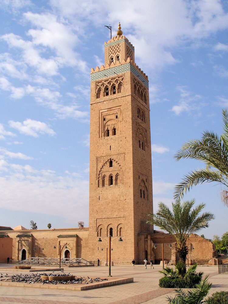 Iconic Koutoubia Mosque in Marrakech, Morocco, surrounded by palm trees under a clear blue sky.