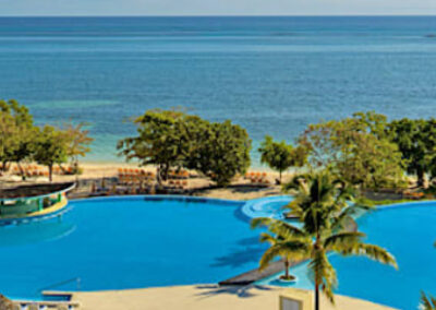 Beachfront Resort in Jamaica with Ocean View Pool – April 2025 - Mini Travel Adventures 4 Us Aerial view of a beachfront resort in Jamaica with palm trees and oceanfront pools.