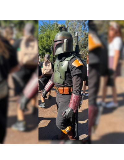 Boba Fett character walking in Star Wars Galaxy’s Edge at Disneyland, surrounded by park guests.