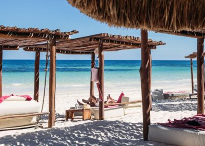 Beach cabanas with canopy beds overlooking the ocean at a couples resort in Tulum.