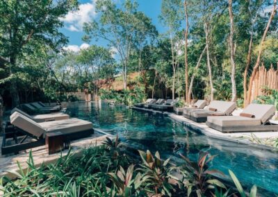 Serene jungle pool with modern loungers and tropical surroundings.