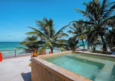Secluded pool area at a boutique Tulum resort for couples, with ocean views and palm trees.