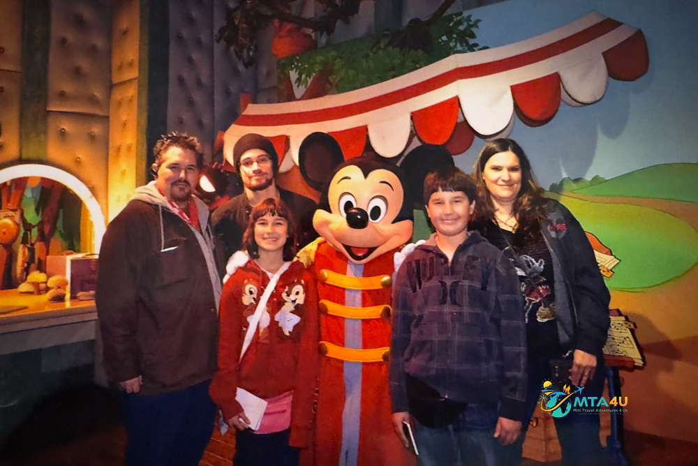 Family Meets Mickey Mouse on First Budget Disneyland Trip (2012) Family of five smiling with Mickey Mouse in his dressing room at Disneyland during their first budget-friendly vacation in 2012.