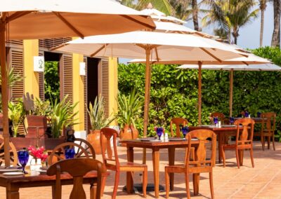 Outdoor dining setup at Dreams Tulum Resort with wooden tables and white umbrellas.