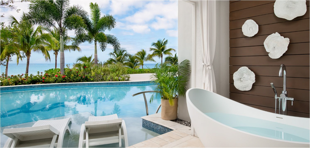 Private Patio and Outdoor Soaking Tub at Sandals South Coast Outdoor bathtub and two lounge chairs beside a tropical garden pool at Sandals South Coast.