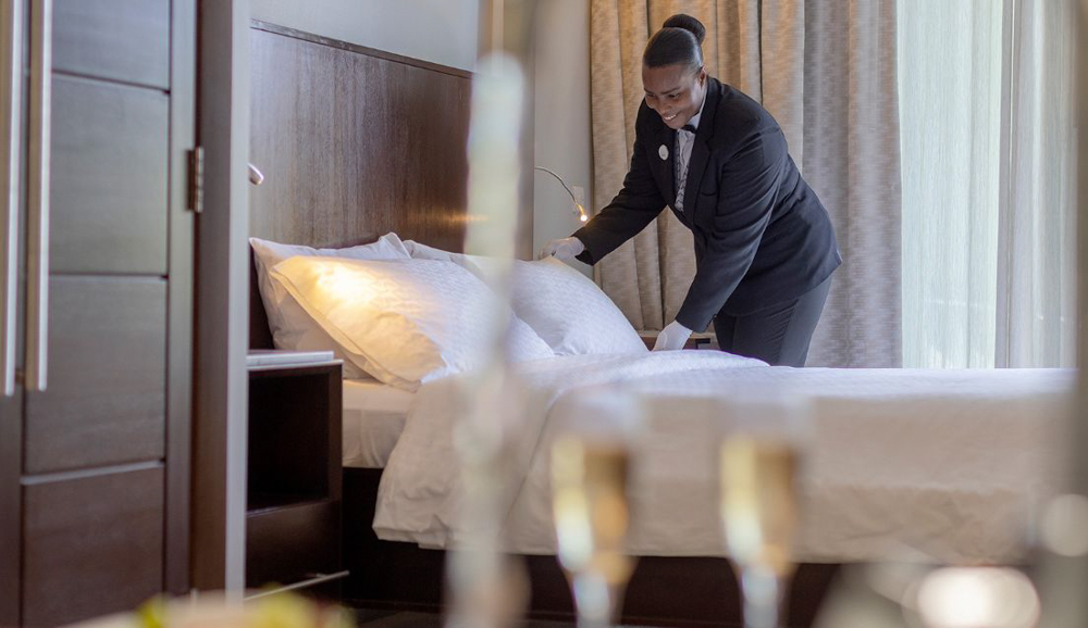 Butler Elite Service at Sandals South Coast Sandals butler smiling while preparing a luxury suite for guests.
