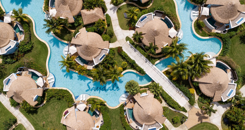 Aerial View of Sandals South Coast Villas and Pools Aerial view of Sandals South Coast featuring lagoon-style pools surrounded by beachfront villas and lush tropical landscaping.