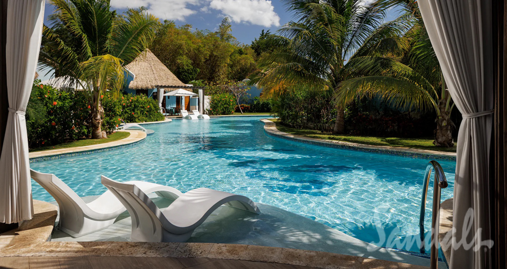 Poolside Serenity at Sandals South Coast Lounge chairs and poolside cabana overlooking a peaceful resort pool surrounded by tropical landscaping.