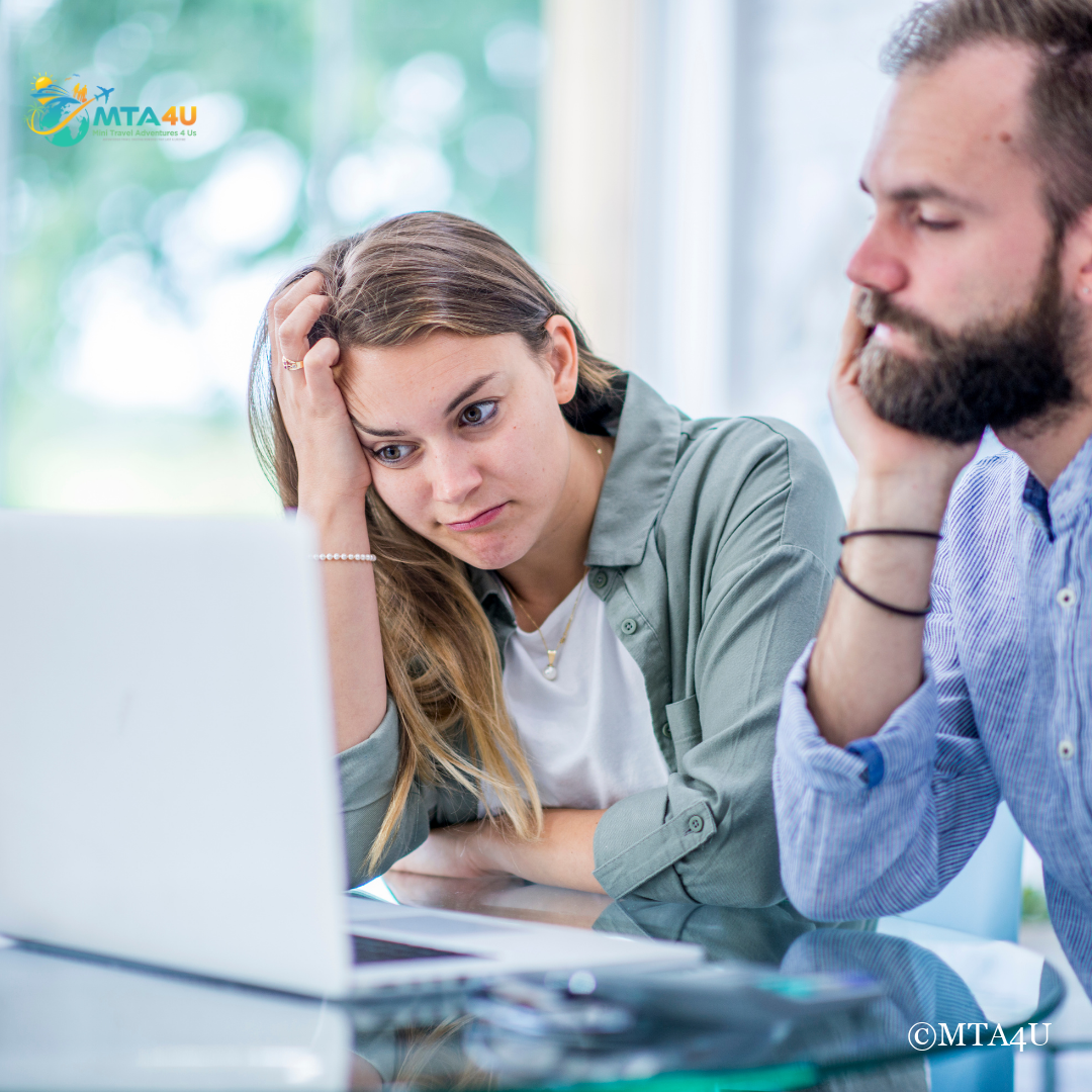 Stressed couple looking at laptop while planning a trip, illustrating vacation planning tips.