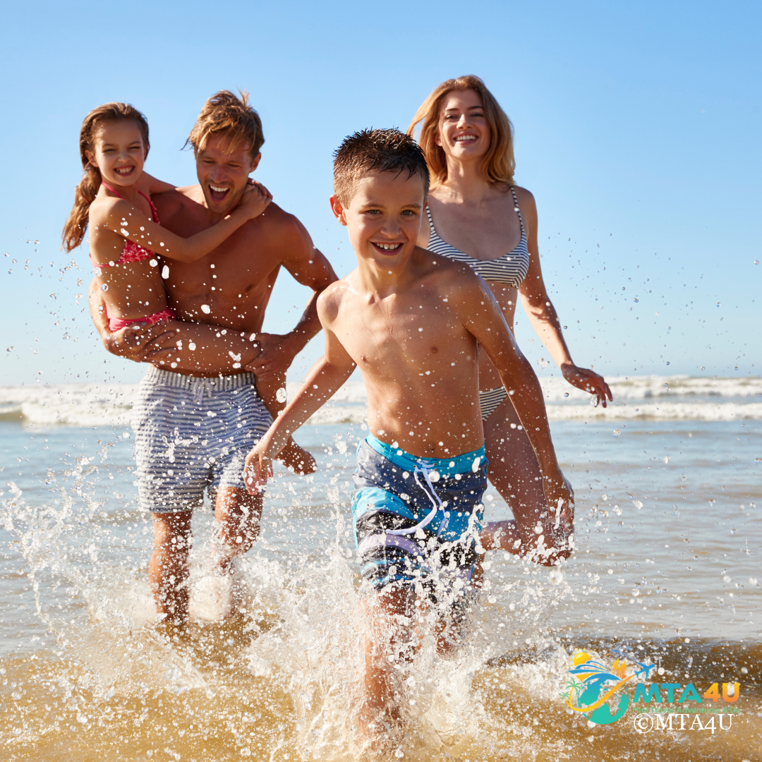 family-beach-vacation-running-water Family beach vacation with parents and children running through ocean waves on a sunny day.