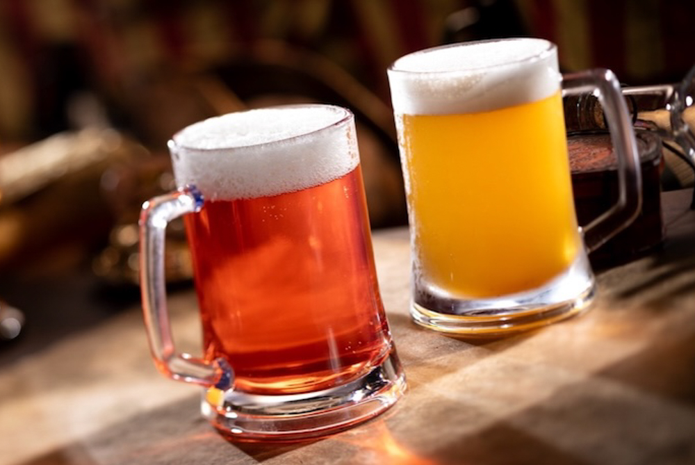 Two frothy pirate-themed drinks served in clear mugs at The Beak and Barrel lounge in Magic Kingdom.
