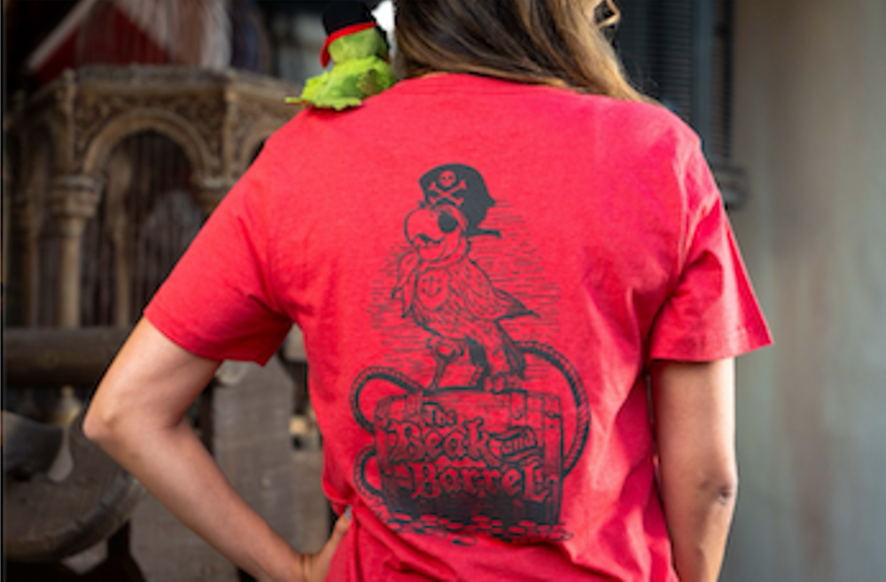 Back of a red Beak and Barrel t-shirt featuring a pirate parrot graphic worn by a guest at Magic Kingdom.