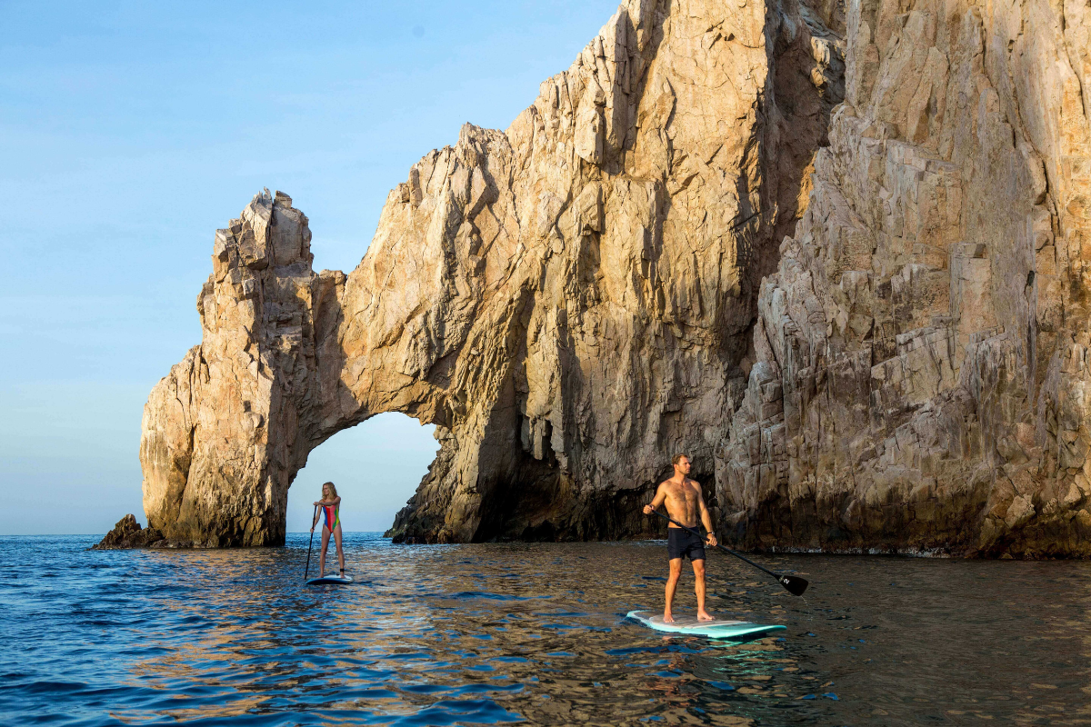 People paddleboarding near El Arco rock formation in Los Cabos, Mexico.