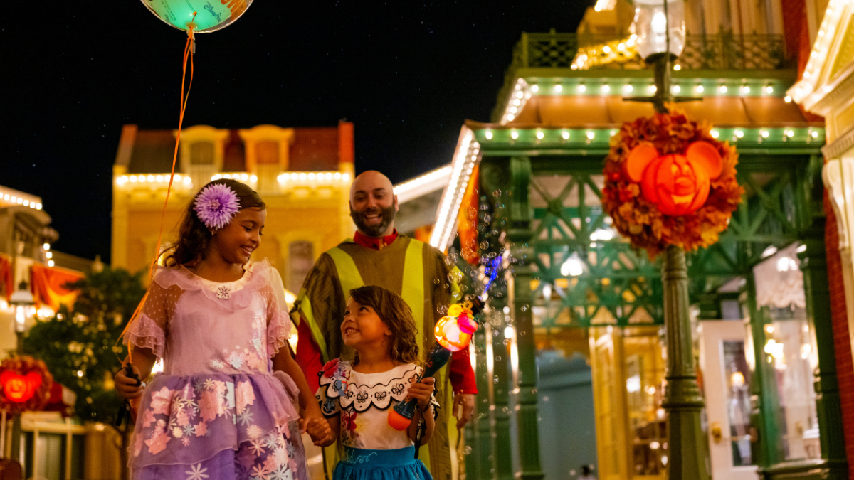 Family walking on Main Street during Mickey’s Not-So-Scary Halloween Party at Magic Kingdom at night.