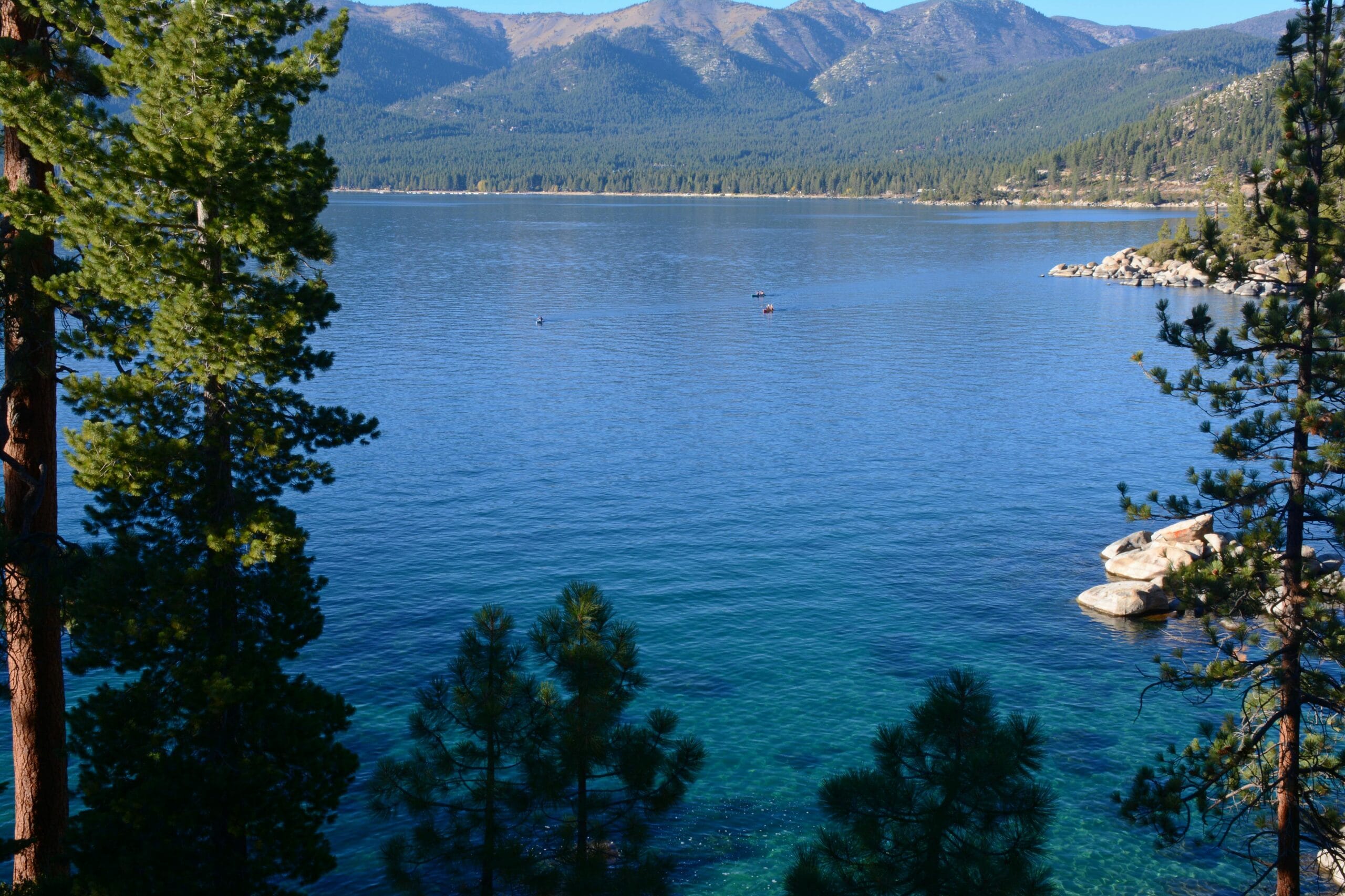 Scenic view of Lake Tahoe’s crystal-clear blue water surrounded by pine trees and mountain peaks in California.