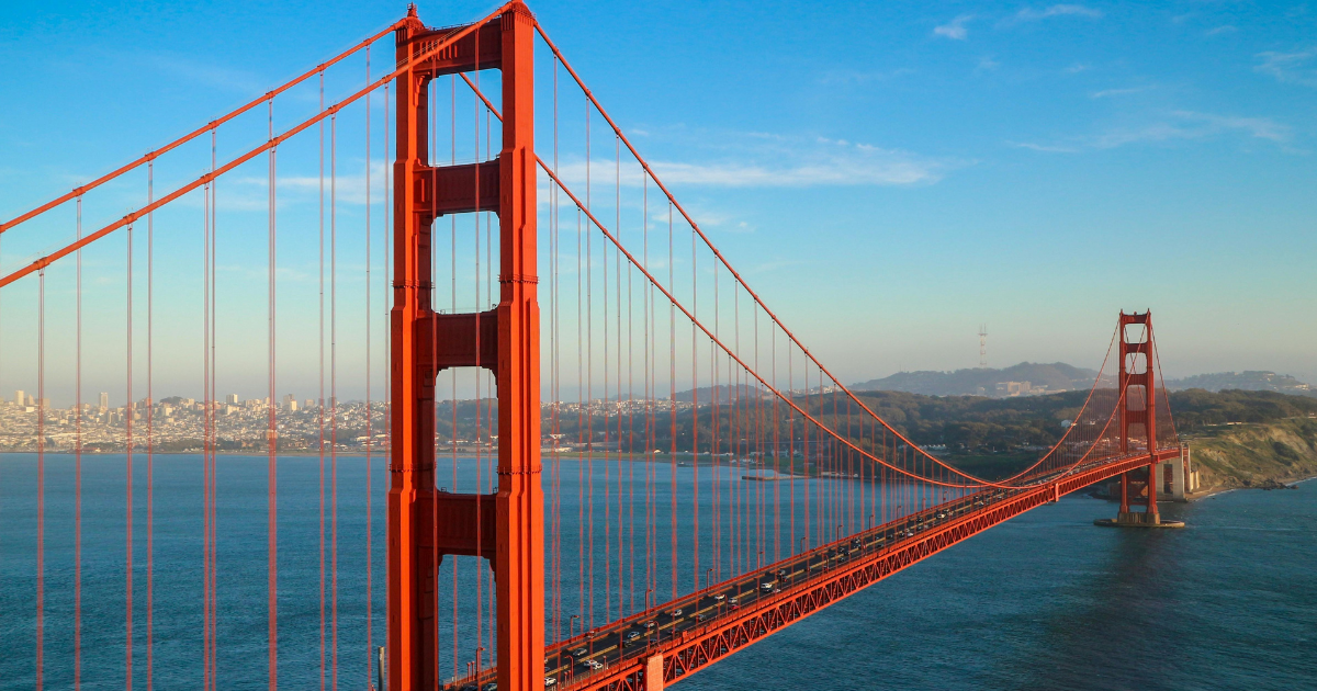 Aerial view of the Golden Gate Bridge spanning San Francisco Bay under a bright blue sky in California.